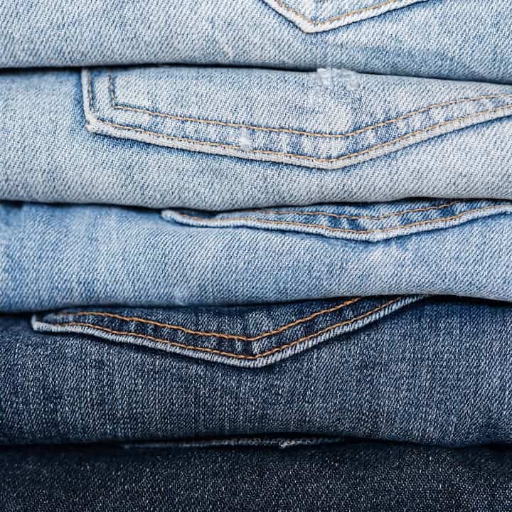 Stack of various denim jeans.