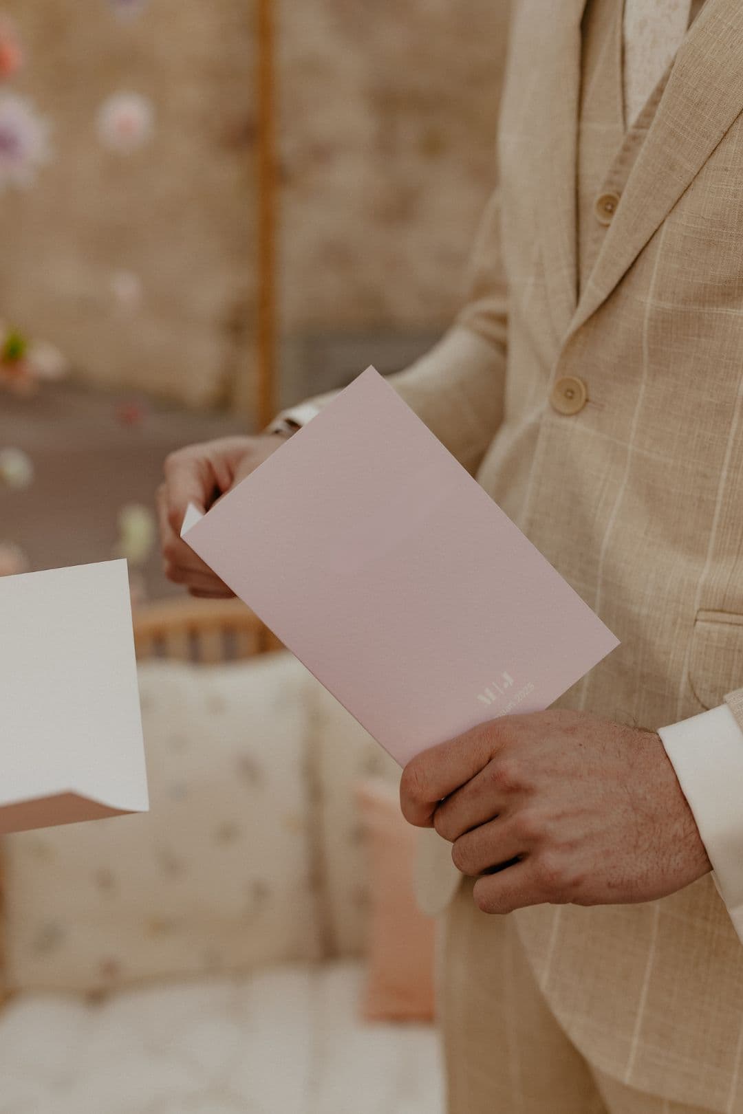 Elegante man in lichtbruin pak met wit overhemd houdt brievenpas in handen, stijlvolle herenmode voor zakelijke, formele en speciale gelegenheden.