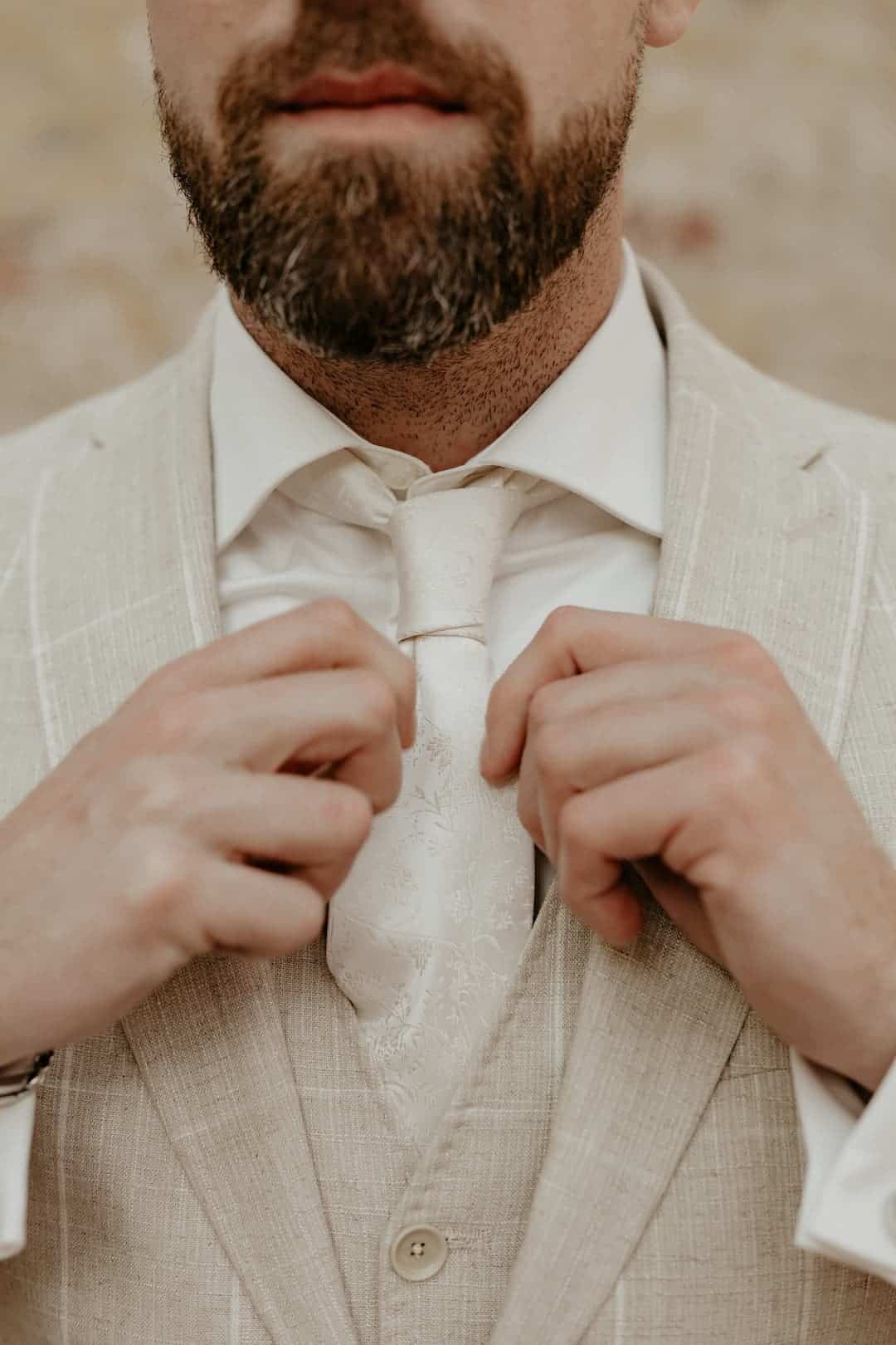 1. Mann keurt elegante trouwkostuum met cravat, close-up, stijlvolle herenmode voor speciale gelegenheden.